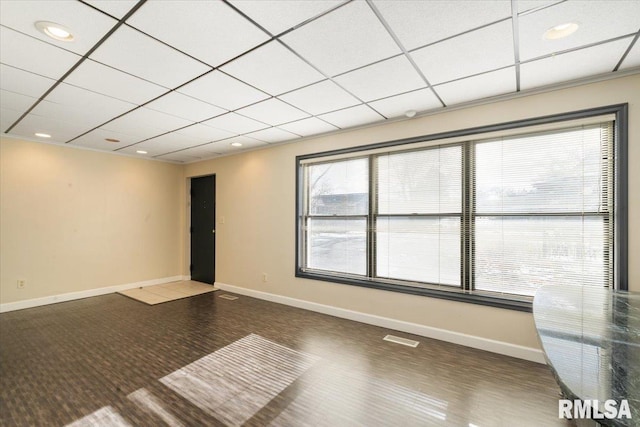 empty room featuring a drop ceiling, visible vents, and baseboards