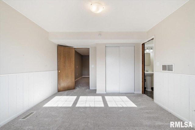 unfurnished bedroom featuring visible vents, carpet floors, and a wainscoted wall