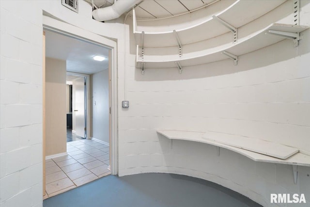 interior space with concrete block wall, finished concrete flooring, and visible vents