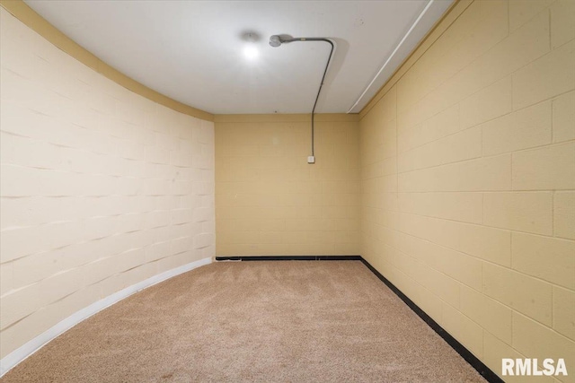 carpeted spare room with concrete block wall