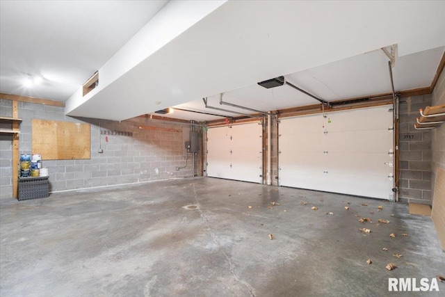 garage with concrete block wall, electric panel, and a garage door opener