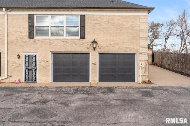 exterior space with brick siding, an attached garage, and a shingled roof