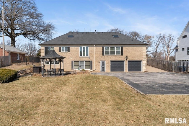 rear view of house featuring a gazebo, driveway, a garage, and fence