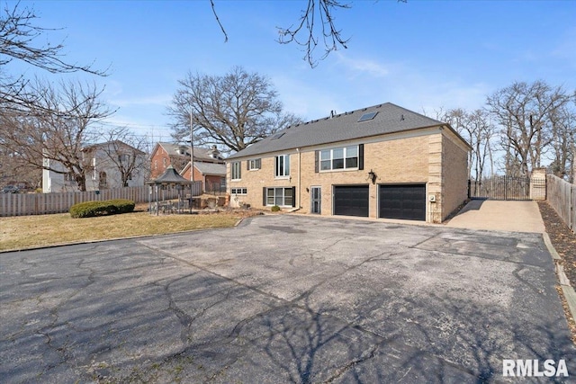 back of property with a yard, an attached garage, driveway, and fence