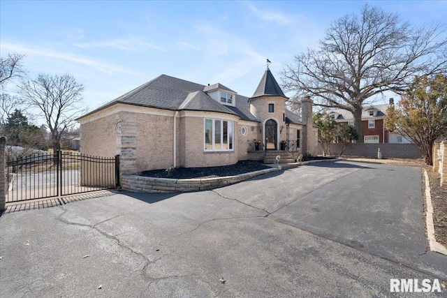 french country home featuring a gate, driveway, roof with shingles, and fence