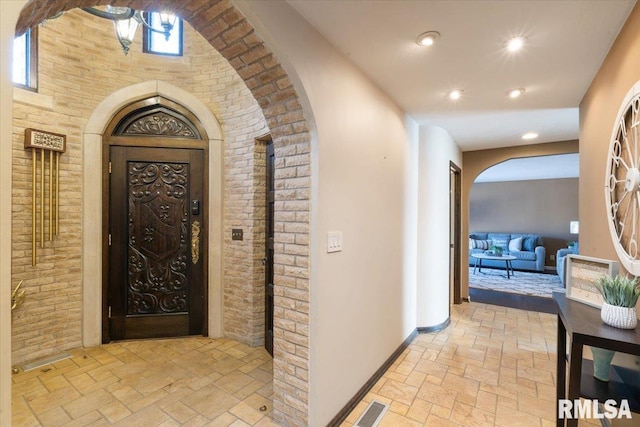 hallway featuring baseboards, arched walkways, and stone tile floors