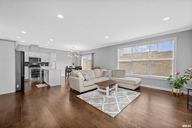 living room with dark wood-type flooring, sink, ornamental molding, and a chandelier