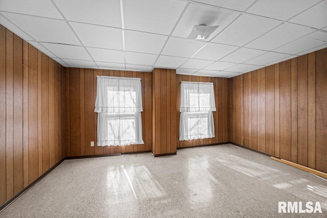 empty room with a paneled ceiling and wood walls