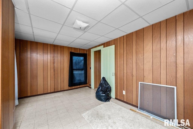 spare room with a drop ceiling and wooden walls