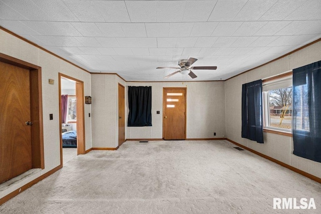 empty room with carpet floors, ceiling fan, and crown molding