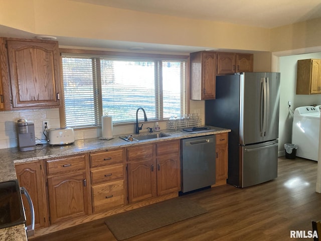 kitchen featuring washer and clothes dryer, appliances with stainless steel finishes, sink, and dark hardwood / wood-style floors