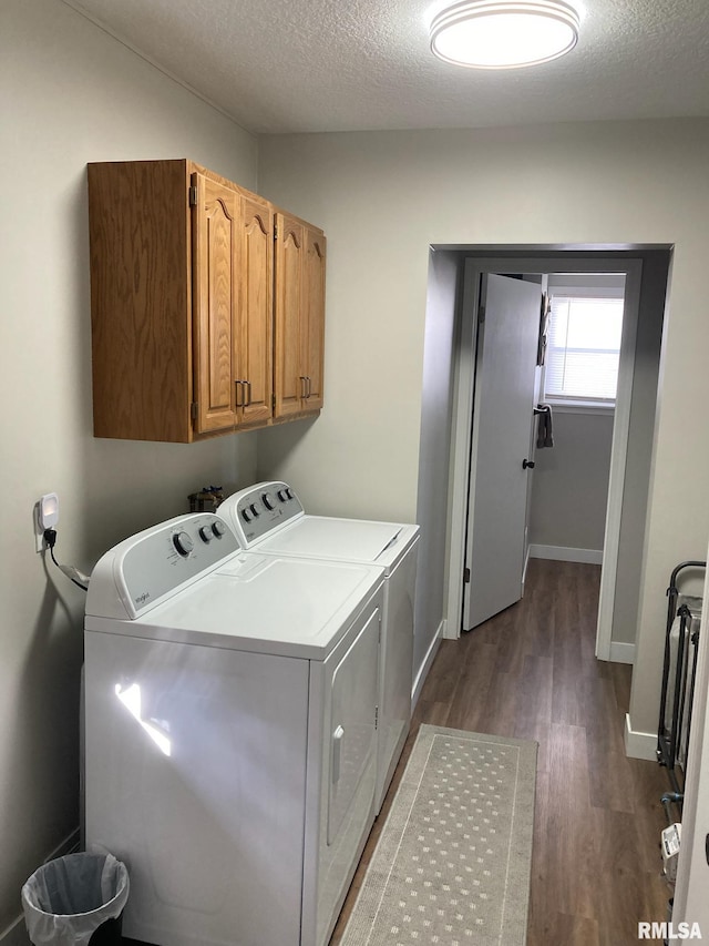 washroom featuring washing machine and dryer, cabinets, a textured ceiling, and dark wood-type flooring