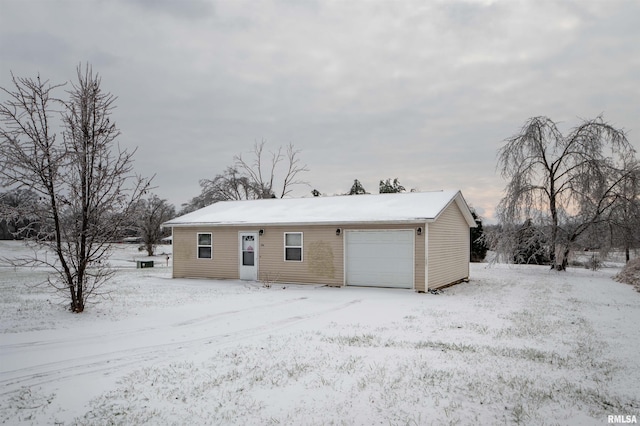 snow covered back of property with a garage