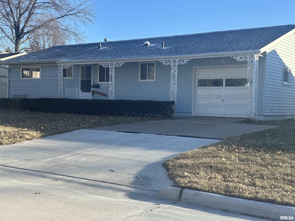 single story home with covered porch, an attached garage, and driveway