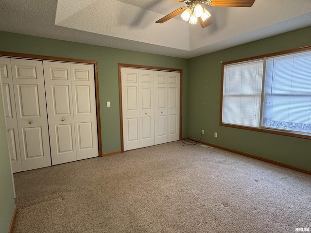 unfurnished bedroom featuring ceiling fan, two closets, and carpet flooring