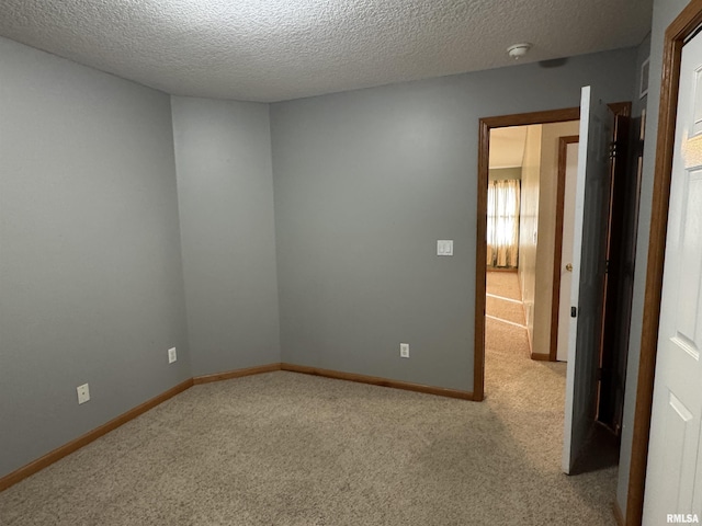 unfurnished room featuring a textured ceiling and light colored carpet