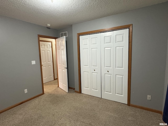 unfurnished bedroom with light carpet, a textured ceiling, and a closet