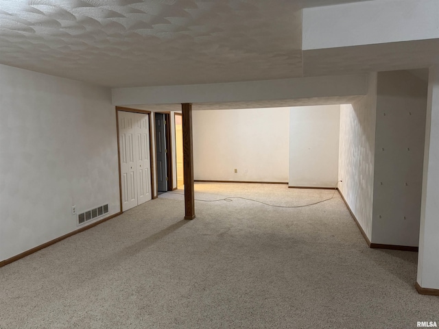 basement with a textured ceiling and light colored carpet