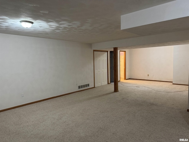 basement featuring a textured ceiling and light carpet