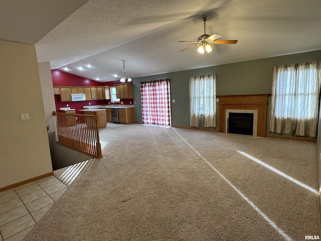 living room featuring ceiling fan, a tiled fireplace, vaulted ceiling, and a wealth of natural light