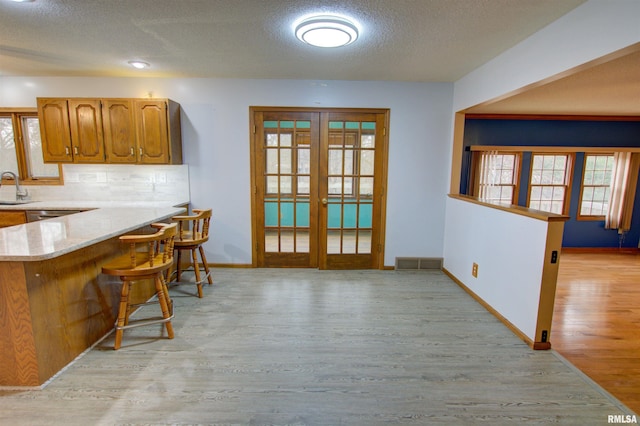 591 Breezy Point Dr, Clinton, IA 52732 - kitchen with light wood-style floors, french doors, baseboards, a breakfast bar area, and decorative backsplash