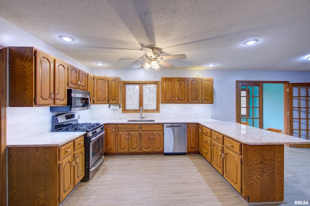 591 Breezy Point Dr, Clinton, IA 52732 - kitchen with appliances with stainless steel finishes, a peninsula, a sink, a textured ceiling, and light countertops