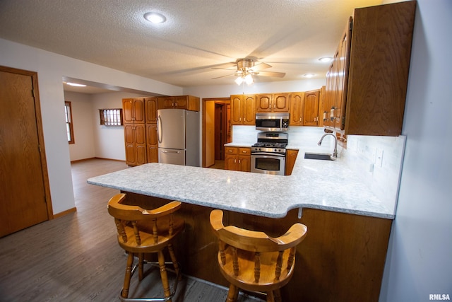 591 Breezy Point Dr, Clinton, IA 52732 - kitchen with stainless steel appliances, a sink, brown cabinetry, light countertops, and a peninsula