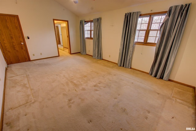 591 Breezy Point Dr, Clinton, IA 52732 - spare room featuring lofted ceiling, baseboards, and light carpet