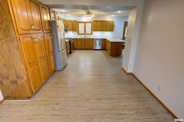 591 Breezy Point Dr, Clinton, IA 52732 - kitchen with appliances with stainless steel finishes, brown cabinets, light wood finished floors, baseboards, and a ceiling fan