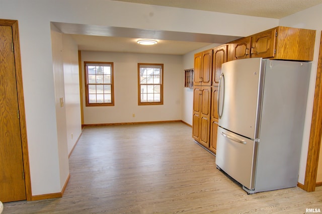 591 Breezy Point Dr, Clinton, IA 52732 - kitchen featuring freestanding refrigerator, light wood-type flooring, baseboards, and brown cabinetry