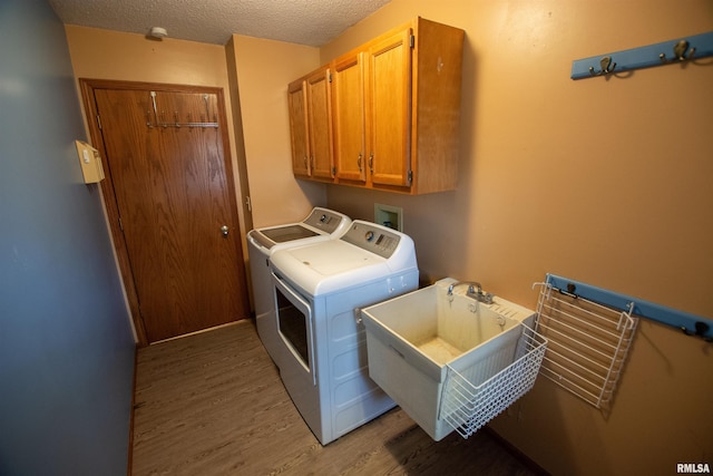 591 Breezy Point Dr, Clinton, IA 52732 - laundry area with cabinet space, washer and dryer, light wood-style flooring, and a textured ceiling