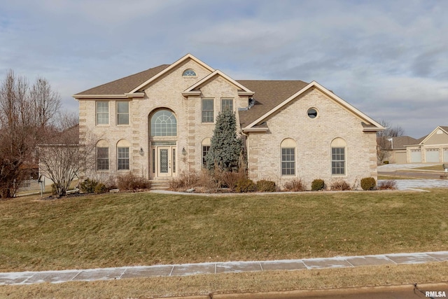 view of front of property featuring a shingled roof, a front lawn, and brick siding