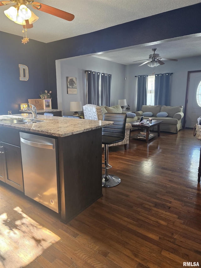 kitchen with dark hardwood / wood-style flooring, sink, stainless steel dishwasher, and light stone counters