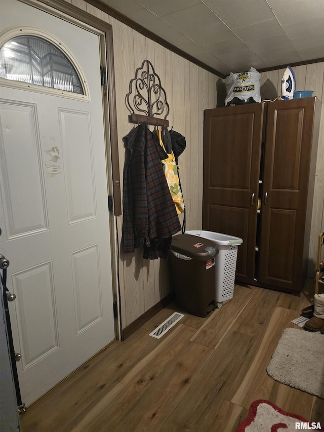 foyer featuring crown molding, hardwood / wood-style flooring, and wooden walls