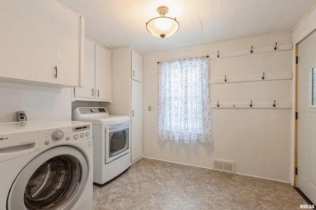 clothes washing area featuring cabinets and washing machine and clothes dryer