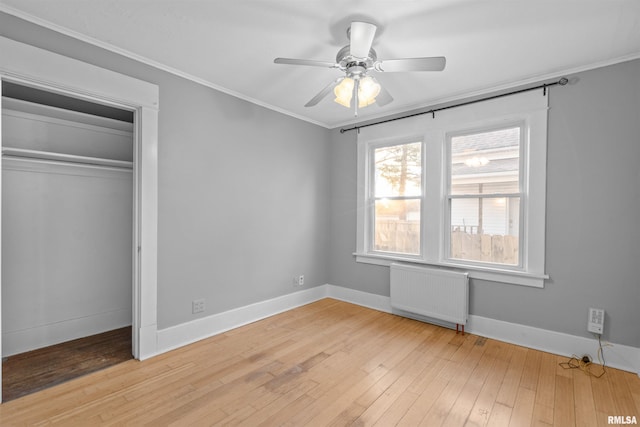 unfurnished bedroom with ornamental molding, radiator, a closet, ceiling fan, and light hardwood / wood-style floors