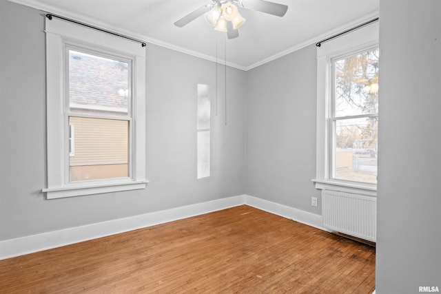 unfurnished room featuring hardwood / wood-style flooring, ornamental molding, radiator heating unit, and plenty of natural light