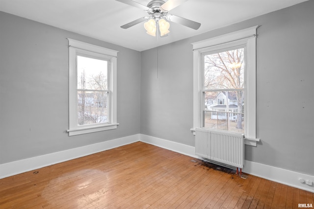 spare room with radiator, light hardwood / wood-style flooring, and ceiling fan