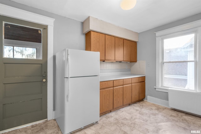 kitchen with white refrigerator, radiator heating unit, and backsplash