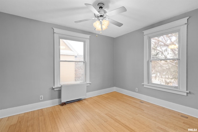 spare room with radiator, ceiling fan, and light wood-type flooring