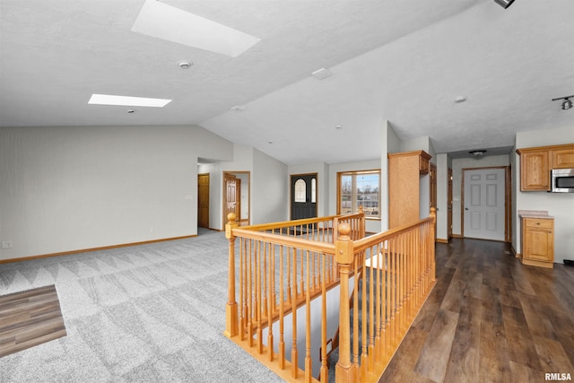 2260 260th Ave, De Witt, IA 52742 - hall featuring an upstairs landing, a skylight, dark wood-type flooring, baseboards, and vaulted ceiling