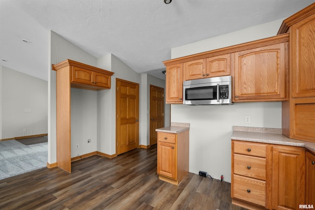 2260 260th Ave, De Witt, IA 52742 - kitchen with stainless steel microwave, dark wood-type flooring, light countertops, and brown cabinetry
