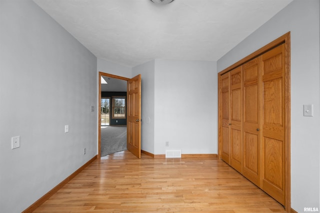 2260 260th Ave, De Witt, IA 52742 - unfurnished bedroom with light wood finished floors, baseboards, and a closet