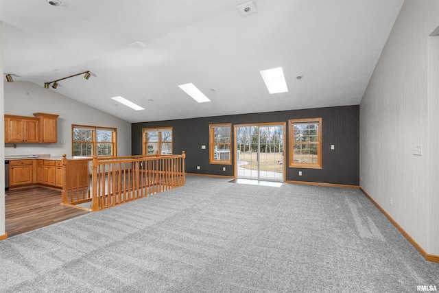 unfurnished living room featuring lofted ceiling with skylight, plenty of natural light, and light carpet