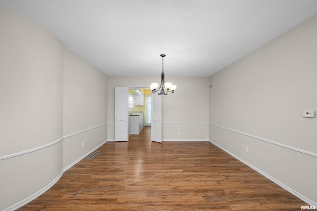 unfurnished dining area with hardwood / wood-style floors and a notable chandelier