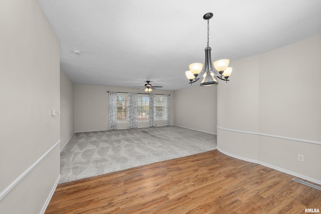 interior space with ceiling fan with notable chandelier and wood-type flooring