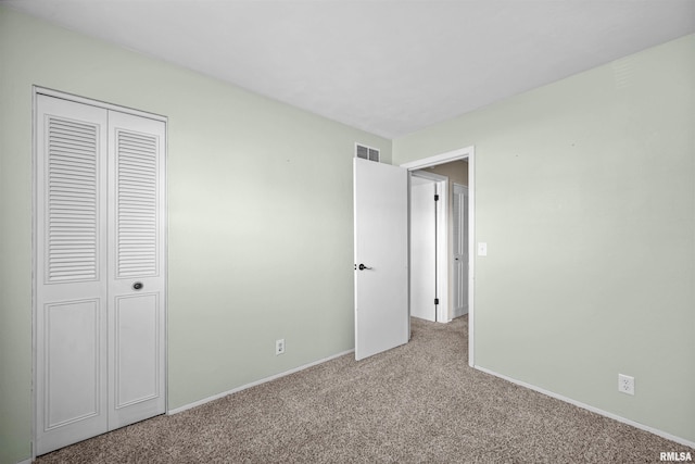 unfurnished bedroom featuring light carpet and a closet