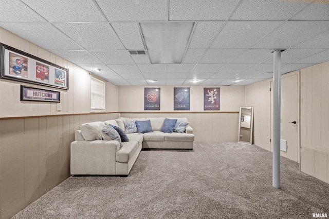 carpeted living room with wood walls