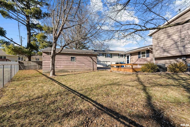 back of house featuring an outbuilding, a deck, and a lawn