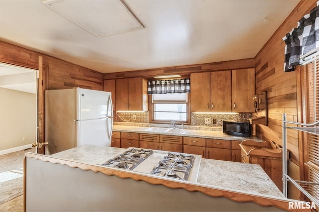 kitchen featuring sink, wooden walls, white appliances, and kitchen peninsula